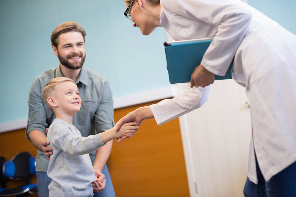 Pediatrician greeting a child and parent